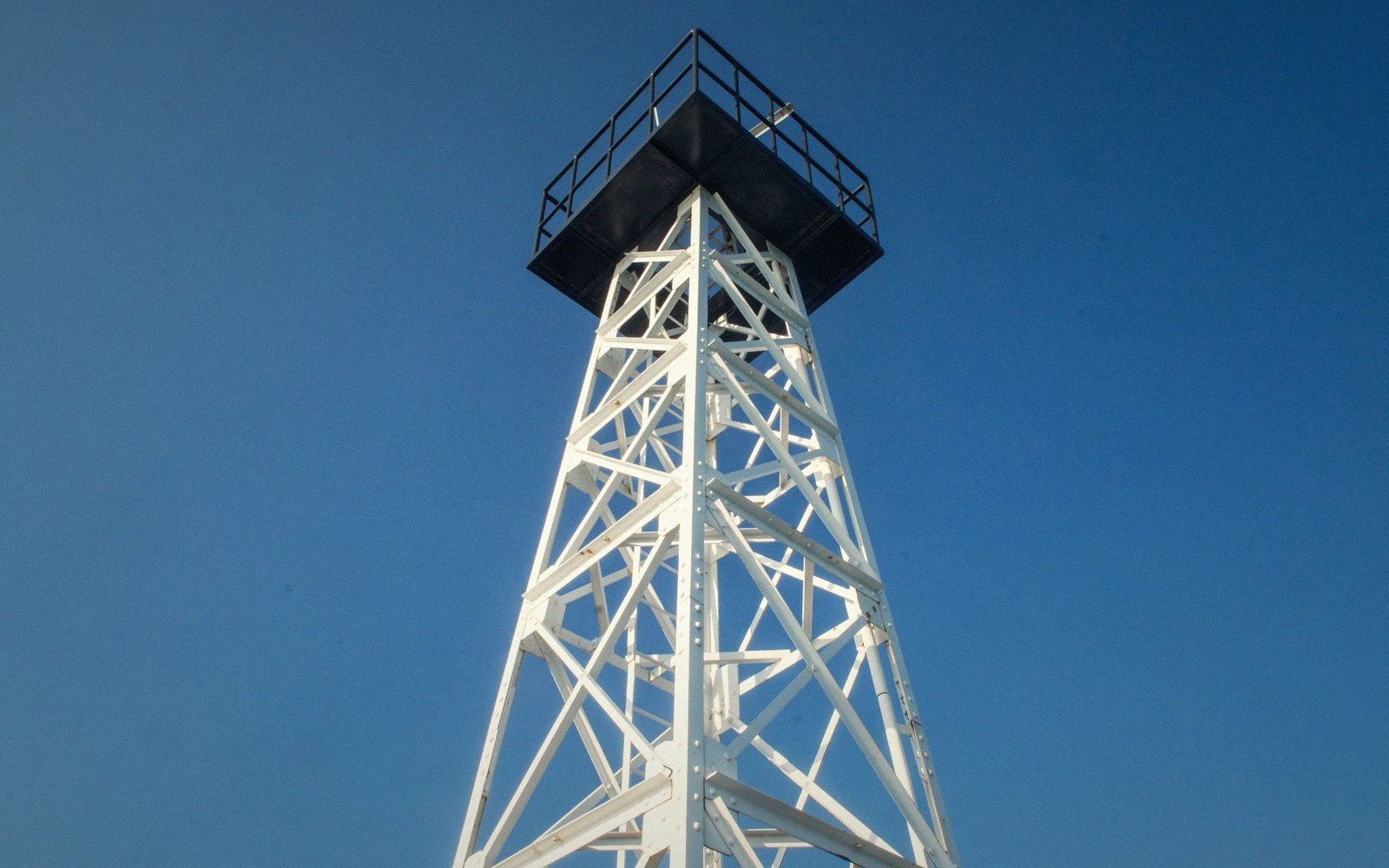 A steel lattice test tower on a flat Nevada salt flat under an overcast sky