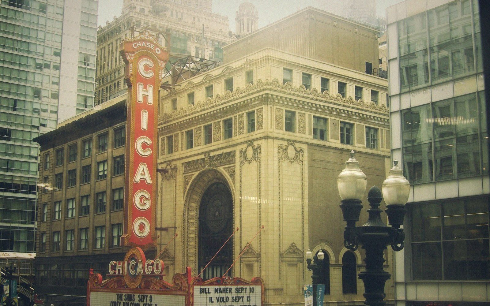 The Chicago Theatre's ornate facade and vertical marquee sign amid downtown skyscrapers